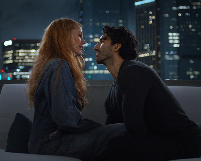 Two people sitting closely on a rooftop at night, city lights in the background, related to Travis Kelce and Taylor Swift. Two people sitting closely on a rooftop at night, city lights in the background, related to Travis Kelce and Taylor Swift.