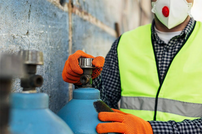 Worker handling gas cylinder with safety gear, highlighting life-saving safety measures.
