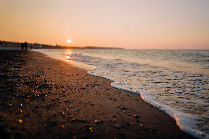 Sunset on a sandy beach with waves gently reaching the shore; a peaceful, life-saving scene.
