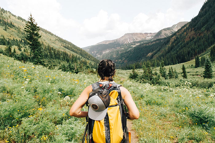 A hiker with a yellow backpack walks through a lush valley, showcasing life-saving outdoor exploration.