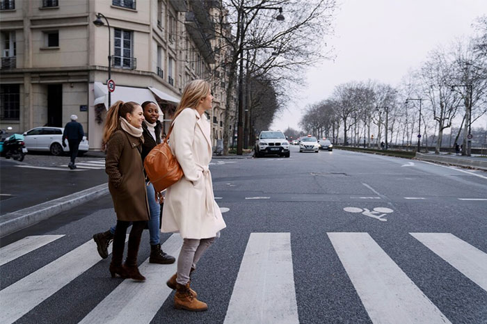 Three women crossing a city street at a pedestrian crosswalk, showcasing life-saving awareness in urban settings.