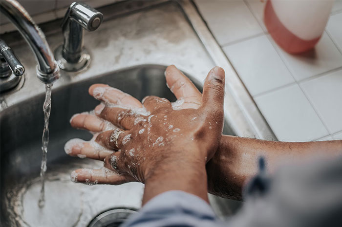 Hands being washed with soap at a sink, demonstrating a life-saving hygiene tip.