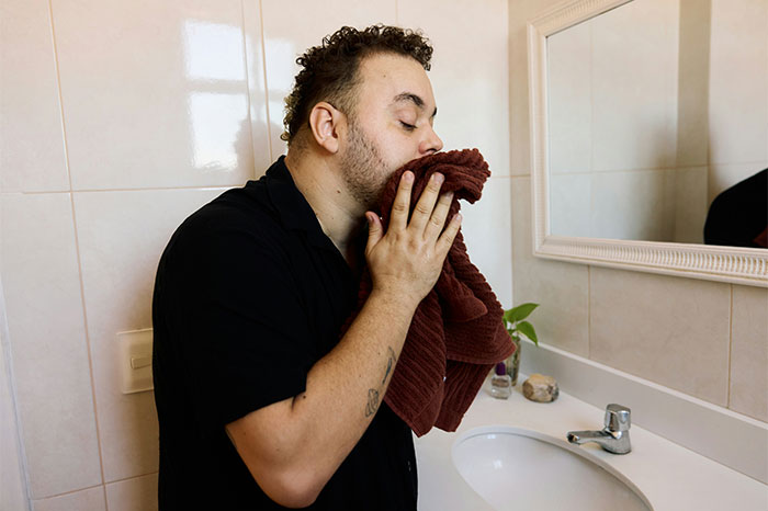 Man drying his face with a towel in the bathroom, highlighting life-saving hygiene habits.