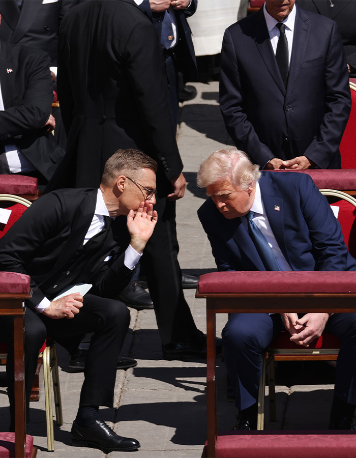 Man in a suit whispering to another man at a formal event, focusing on lip reader keywords.