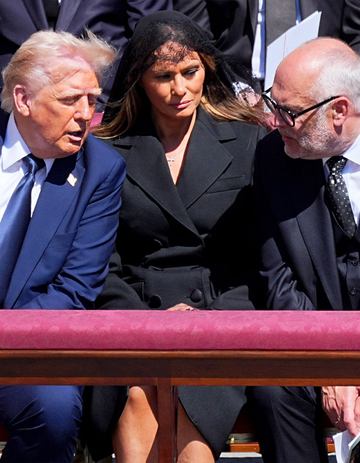 Melania in black, with Trump at a formal event. Lip reader speculation about whispered words at a significant gathering.