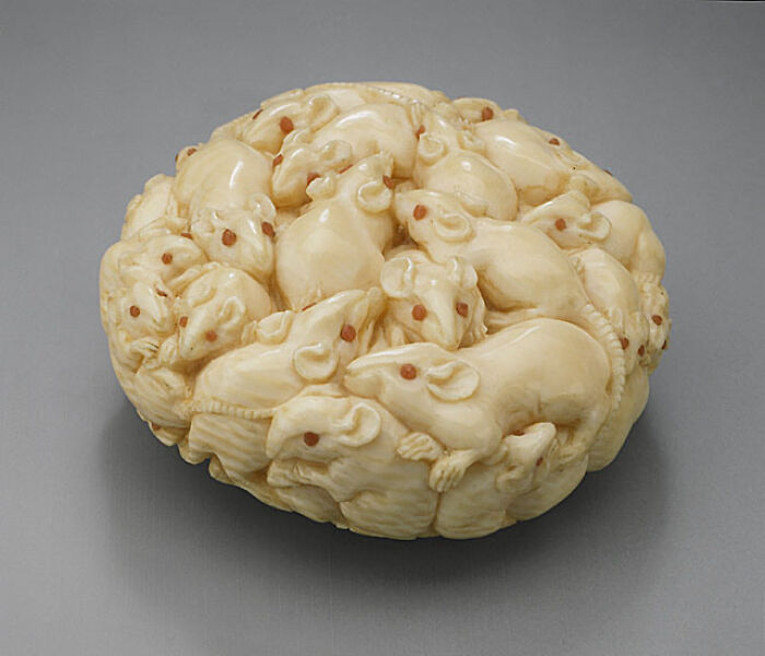 Historic artifact carved from ivory, depicting a cluster of mice intricately sculpted together.