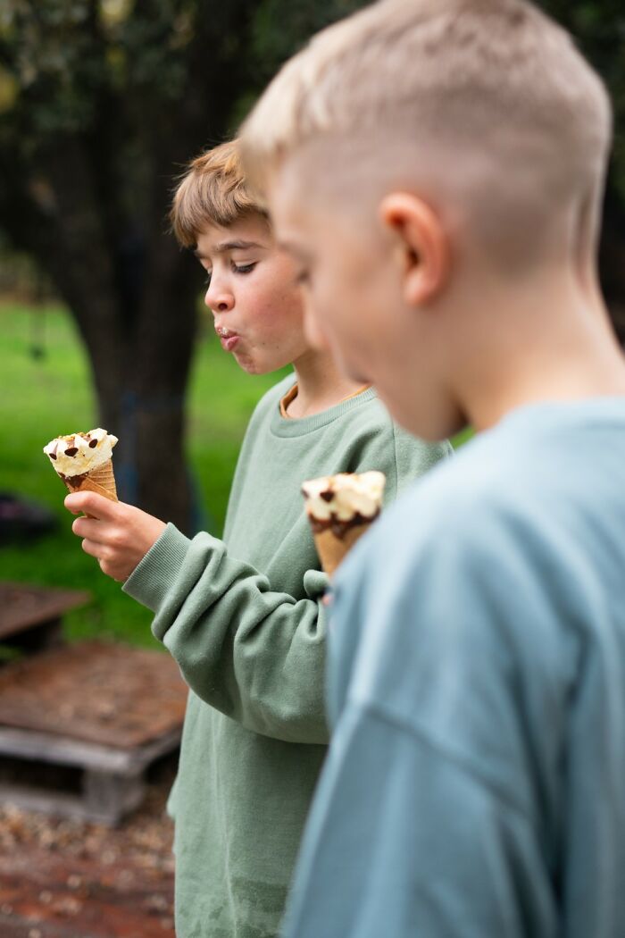 Two children enjoying ice cream cones outdoors, showcasing their comedic expressions.