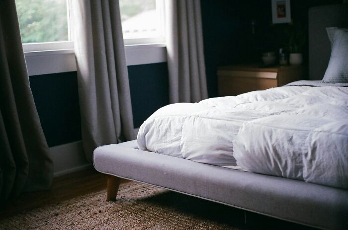 Cozy bedroom with rumpled white bedding on a low-profile bed frame, illustrating adult living habits.