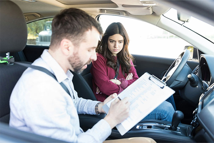 Woman looks frustrated while a man with a clipboard speaks to her inside a car, illustrating awkward interactions during pregnancy.