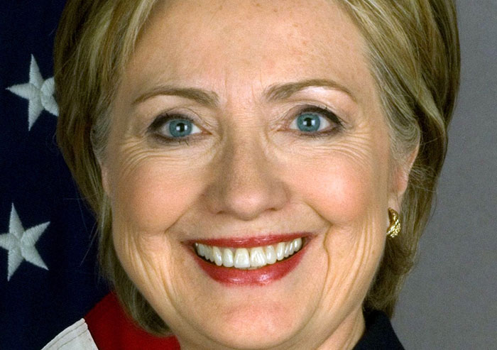 Close-up of a smiling woman with blonde hair and an American flag in the background for moments in history importance.