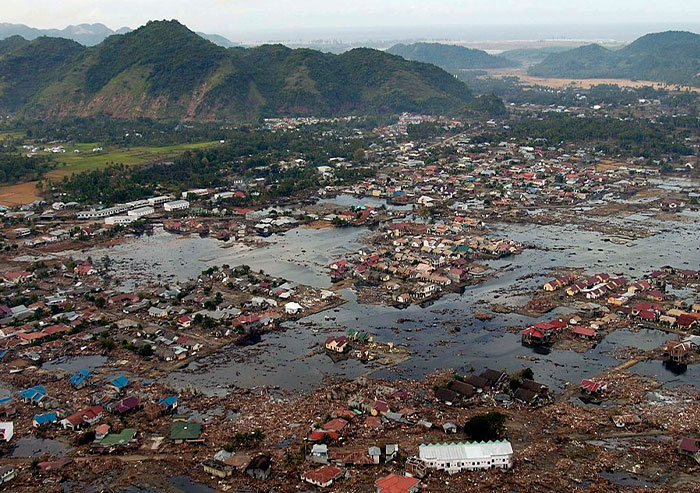Aerial view of a flooded town with debris and destroyed buildings, showing a significant moment in history.