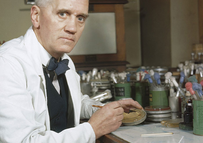Scientist in a lab coat conducting research with petri dishes and lab equipment, symbolizing moments in history.