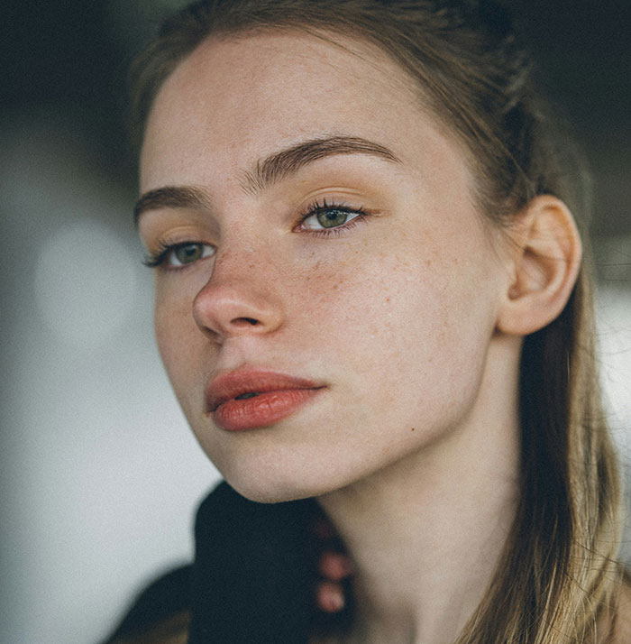 A woman with minimal makeup and natural beauty, showcasing a calm expression, embodying unhinged beauty hacks.