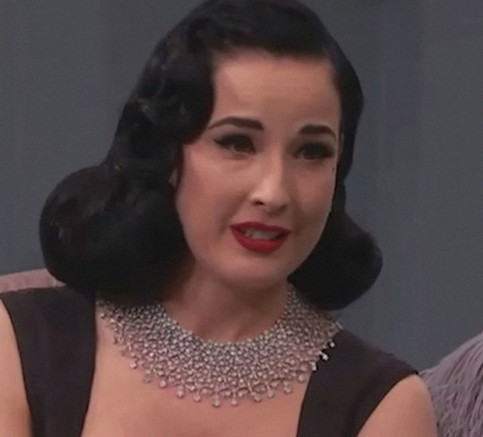 Woman with vintage hairstyle and bold makeup, wearing a sparkling necklace, showcasing unique beauty hacks.