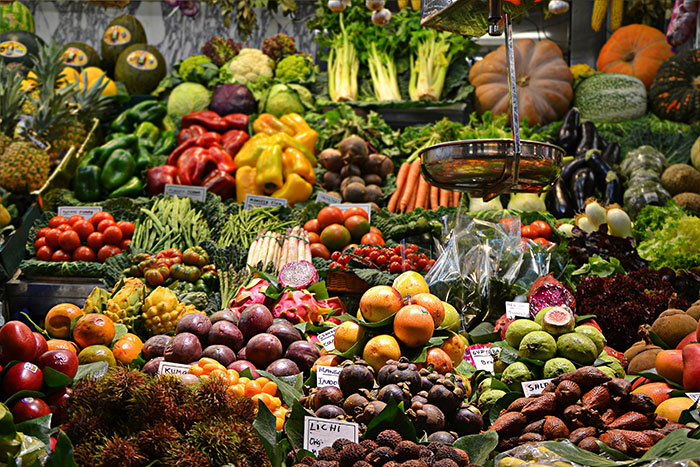 Colorful market stall with an array of fruits and vegetables, featuring scales above.