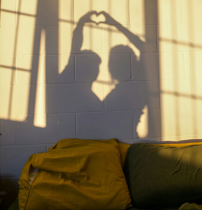 Shadow hand heart on wall near sofa, showcasing unhinged beauty hacks.
