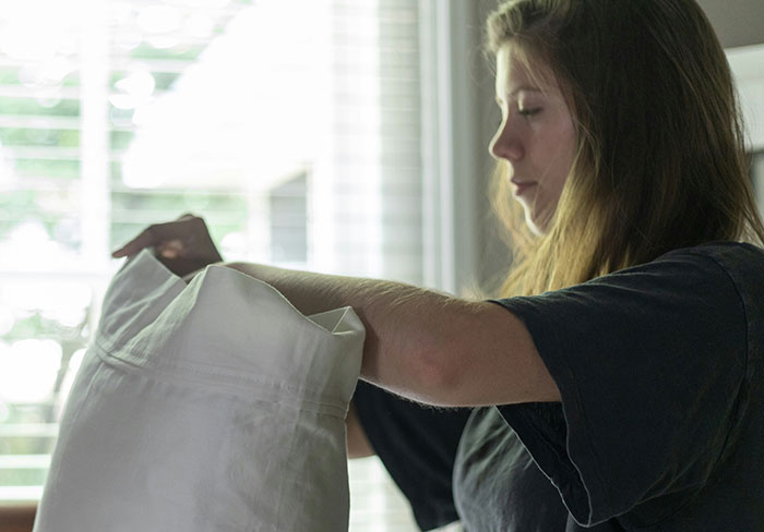 A woman trying out a beauty hack, using a pillowcase near a bright window.