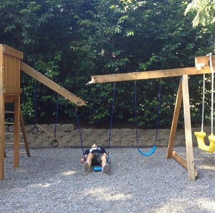 Person lying on a swing in an odd position, surrounded by playground equipment, highlighting a random cursed image.
