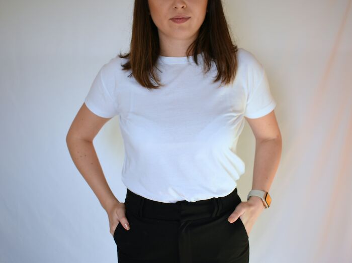 Woman in white shirt and black pants standing with hands in pockets, expressing frustration related to exes' actions.
