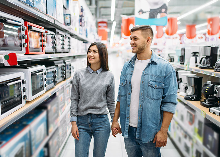 Couple exploring kitchen appliances in a store, holding hands, illustrating marriage hacks.