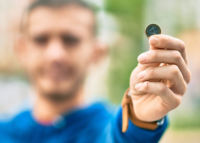 Man in blue jacket holding a coin, showcasing creative marriage hacks in focus.