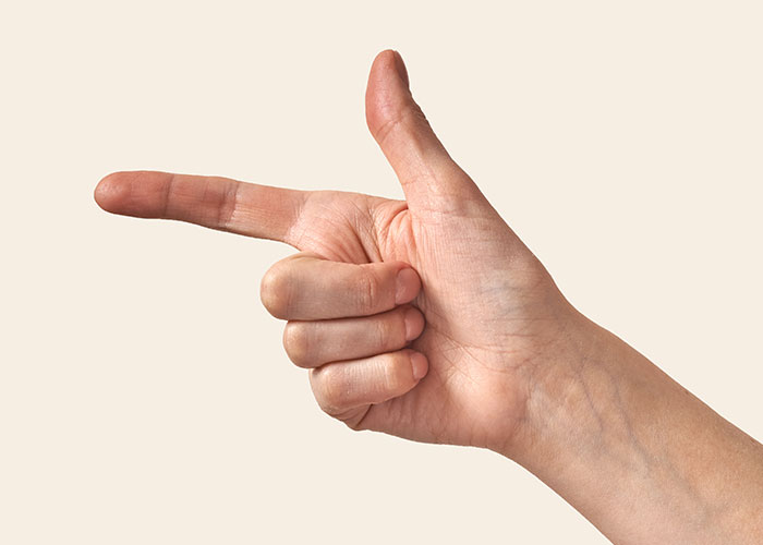 Hand gesture resembling a finger gun, illustrating a playful marriage hack concept.