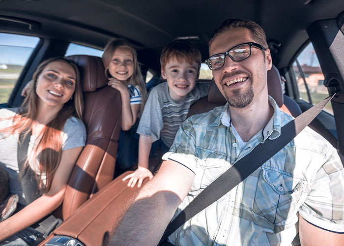 Family enjoying car ride together, smiling and capturing the moment.