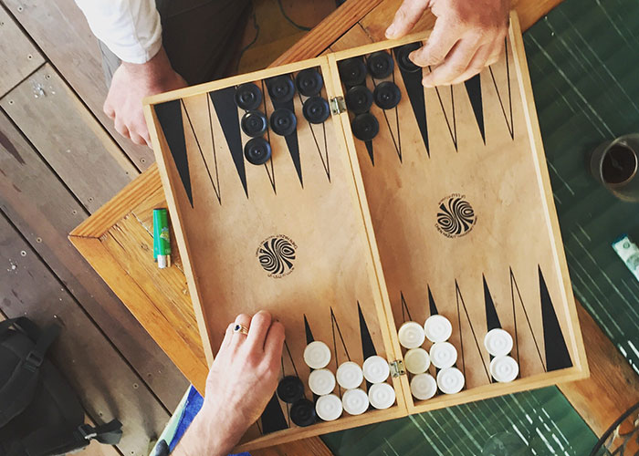 Two people playing backgammon, engaging in an exciting board game, emphasizing teamwork and strategy in marriage hacks.