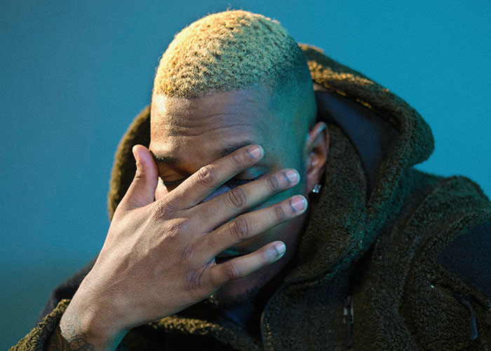 Man with hand on face, highlights emotional response as women decenter men in diverse contexts.