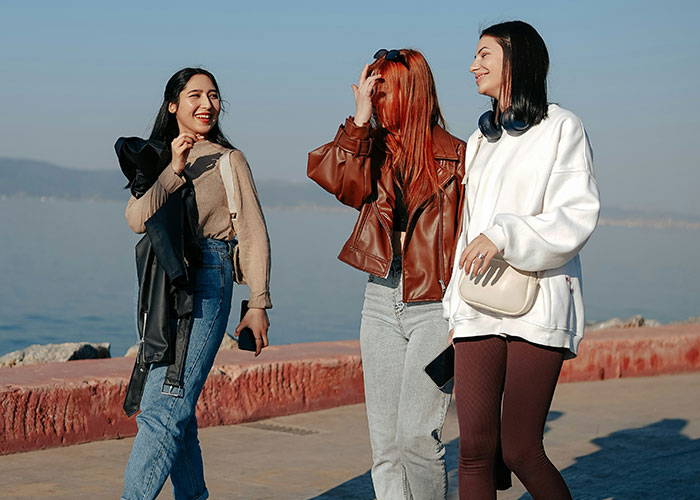 Three women enjoying a sunny day by the sea, embodying ways to decenter men.