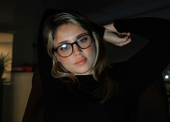 Woman in glasses, reclining thoughtfully, illustrating the concept of women decentering men.