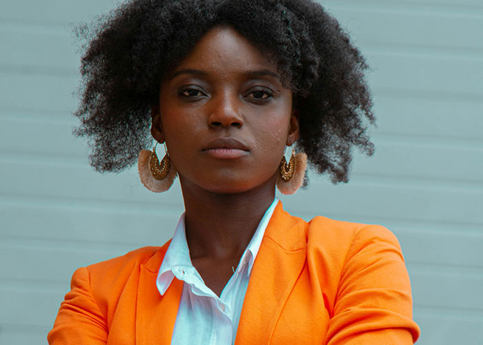 Woman in orange blazer standing confidently, representing ways women decenter men.