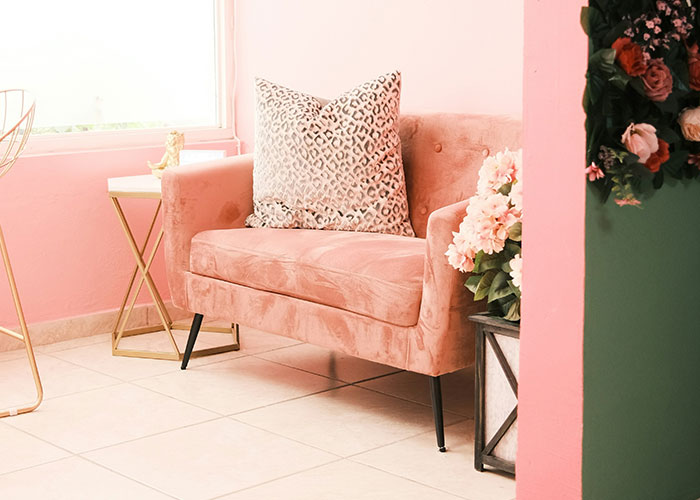 Pink couch with a patterned pillow and floral decor, illustrating ideas to decenter men in a modern interior setting.