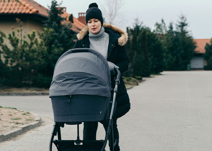 Woman pushing a stroller on a quiet street, showcasing ways to decenter men in everyday life.