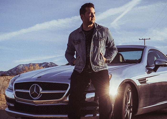Man leaning confidently against a silver Mercedes, showcasing ways women decenter men.