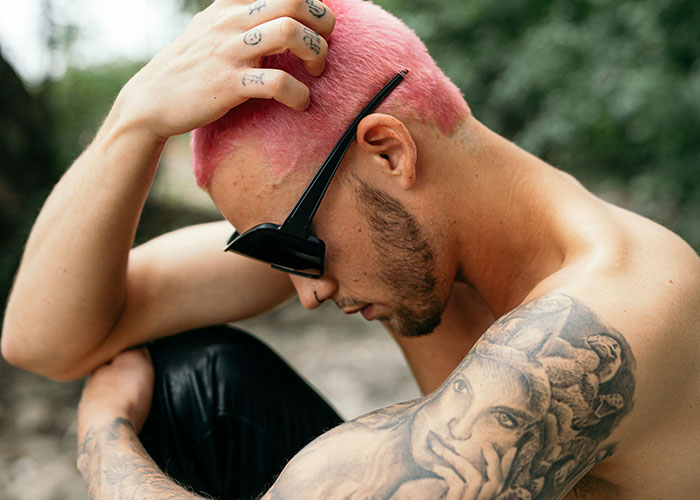 Man with pink hair, sunglasses, and tattoos in profile, illustrating ways women decenter men.