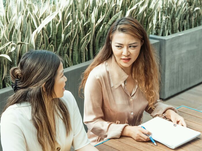 Two coworkers having an awkward conversation in an office setting.