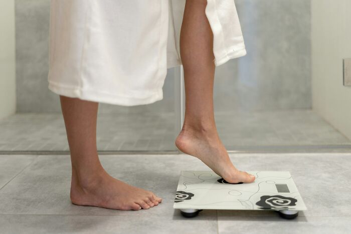 Person in a white robe standing on a bathroom scale, highlighting challenges with coworkers.