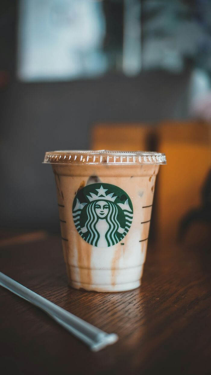 Iced coffee on a wooden table, an unhinged way to distract from coworkers you can't stand at the office.