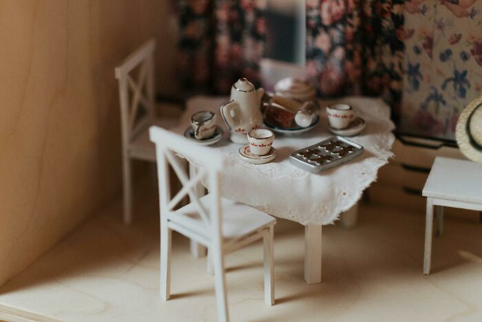 Miniature tea set on a dollhouse table, illustrating unhinged ways to deal with coworkers you can't stand.