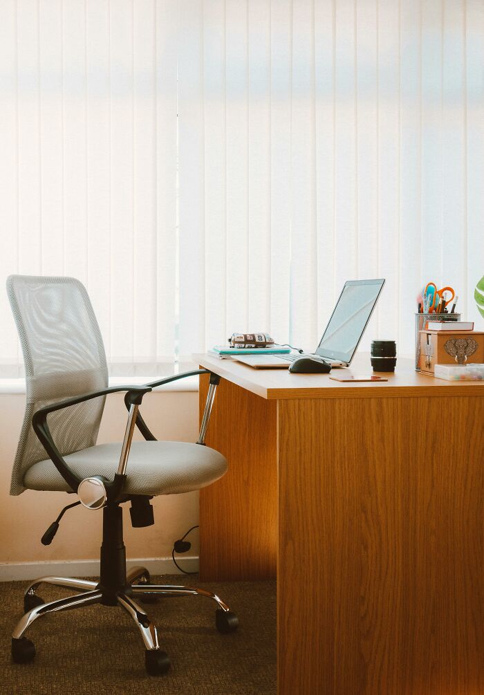 Office desk with an empty swivel chair and laptop, suggesting unhinged ways to deal with coworkers you dislike.