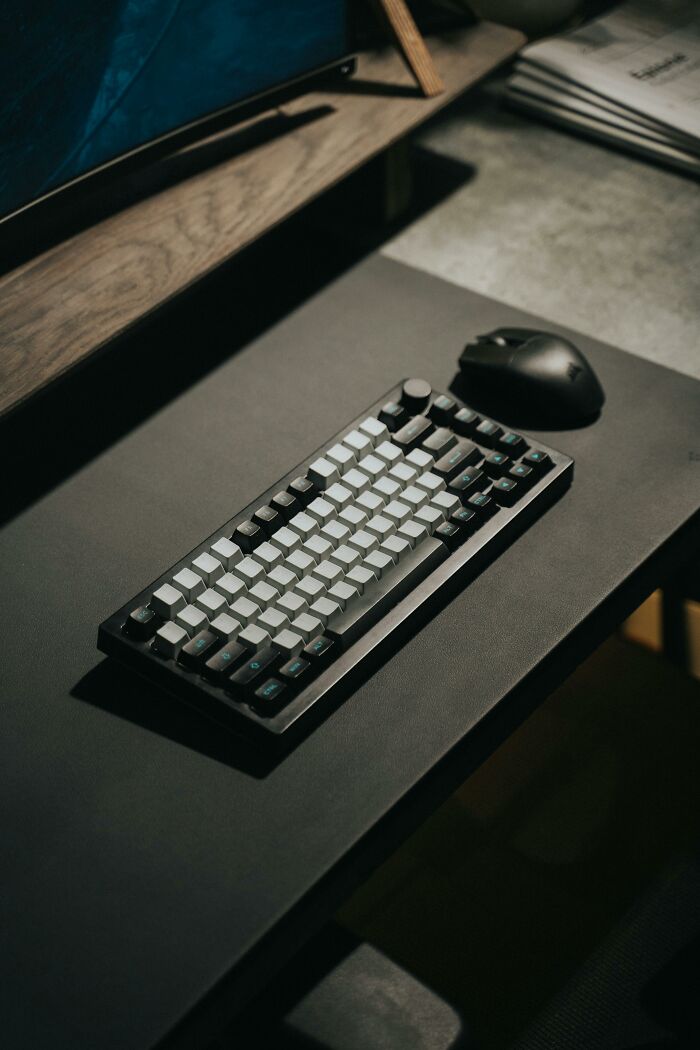 A sleek keyboard and mouse on a dark office desk setup, suggesting a unique approach to difficult coworkers.