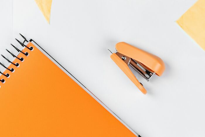 Orange stapler and notebook on desk, illustrating ways to deal with coworkers.