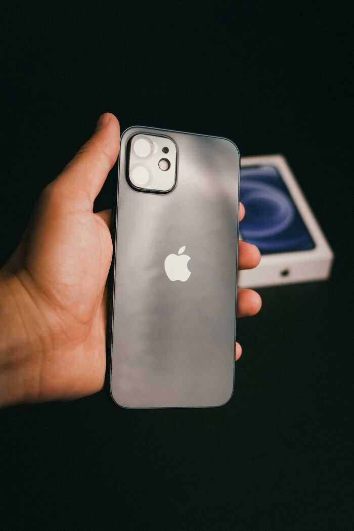 "Hand holding a sleek smartphone against a dark background, symbolizing luxury and expensive weddings trend."