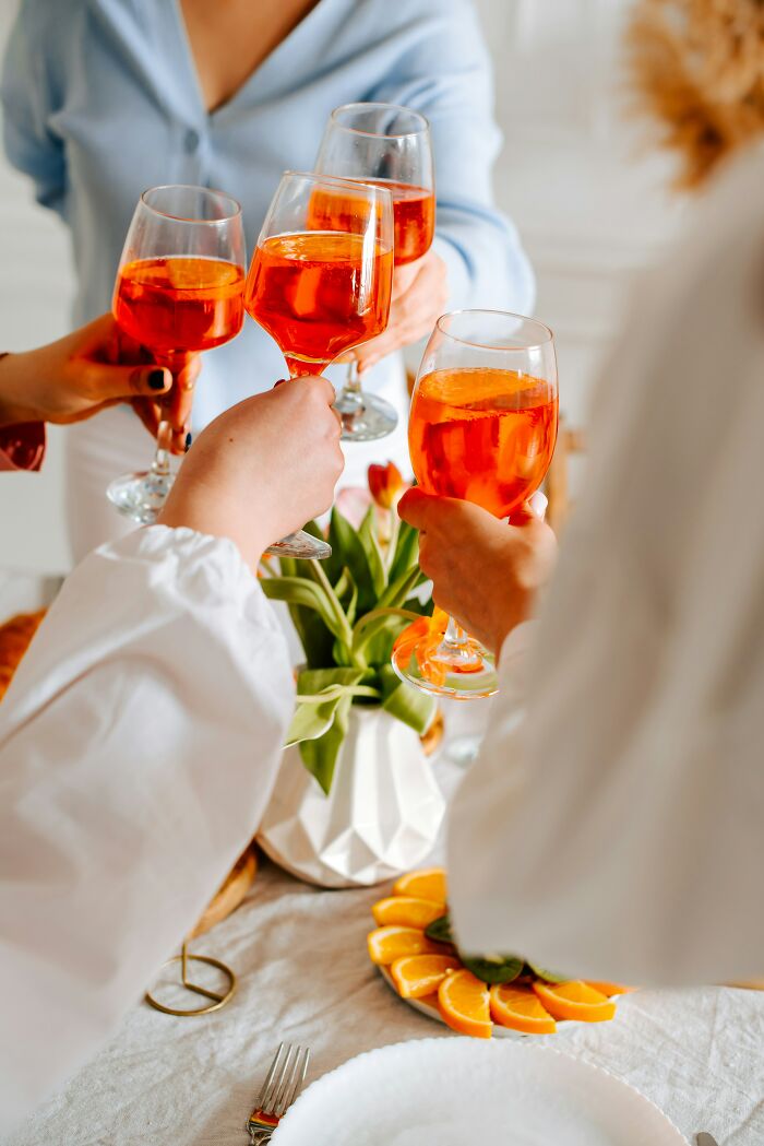Four people toasting with orange drinks at a table set for an expensive wedding celebration.