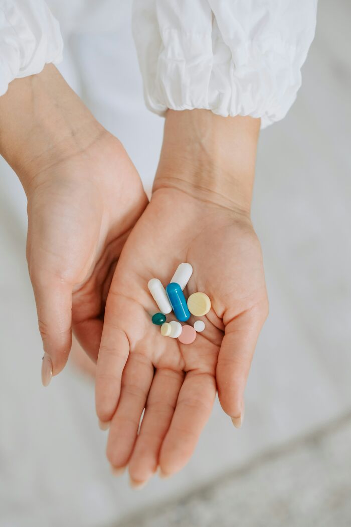 Hands holding a variety of pills, symbolizing modern consumer influences on expensive weddings.