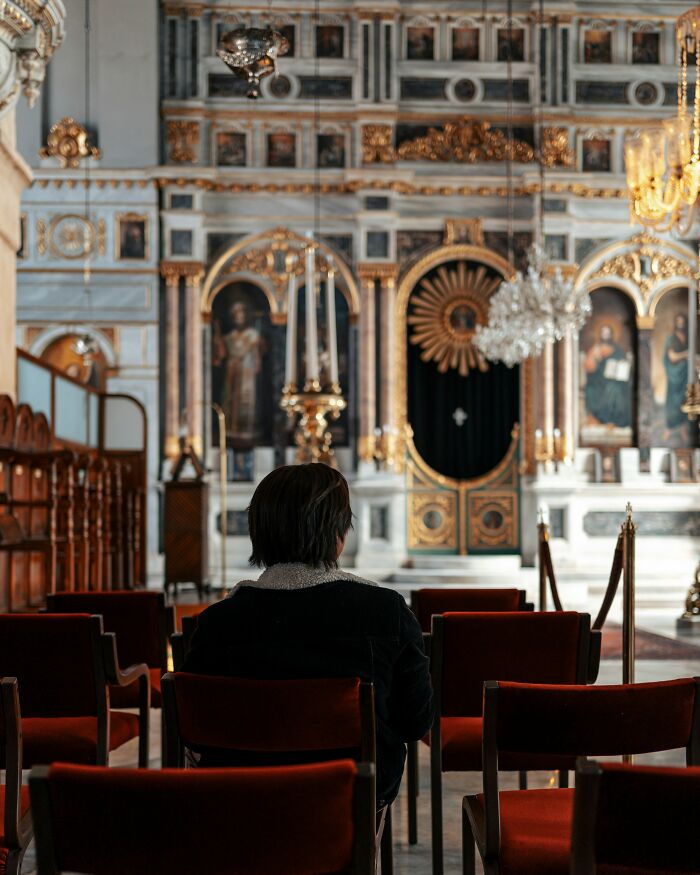 Person seated in a lavishly decorated venue, symbolizing expensive weddings with opulent decor in the background.