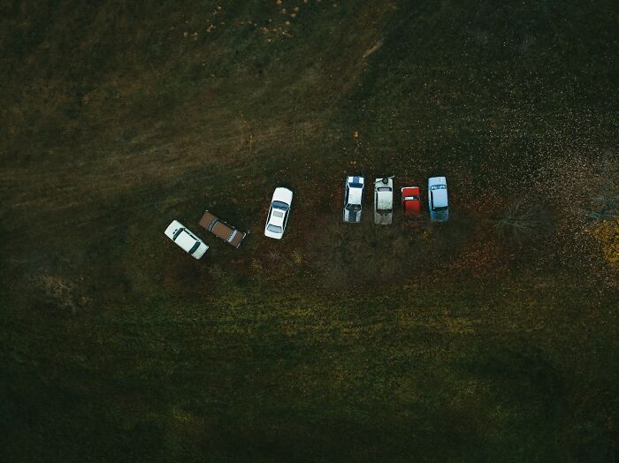 Aerial view of cars parked on grass, illustrating a sense of unease and potential danger avoidance.