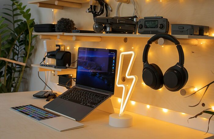 Organized desk with laptop, headphones, and decorative lights, showcasing cleaning rules in home office setup.