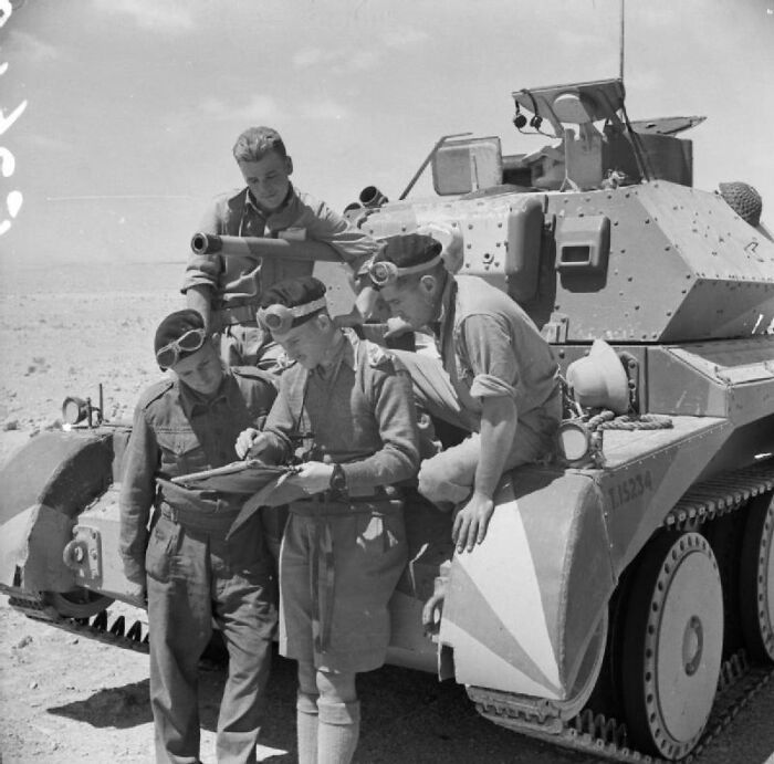 WWII soldiers gathered around tank checking map, showcasing unforgettable moments in wartime history.